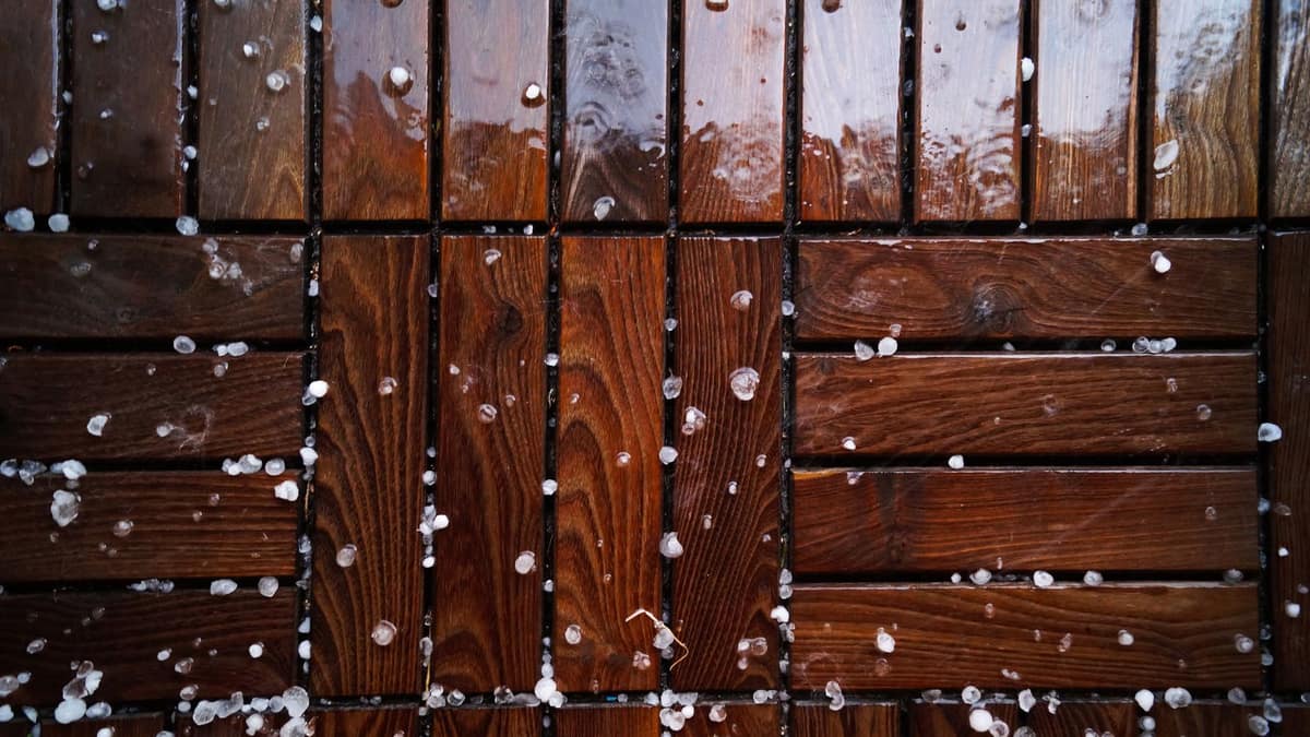 Hailstones scattered across a wet wooden deck after a Texas hailstorm